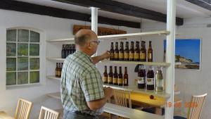 Købmandsgaardens B&B في غيدسير: رجل يقف أمام رف من زجاجات النبيذ