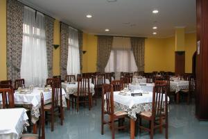 a dining room with tables and chairs with white tablecloths at Hotel El Puente in Sanxenxo