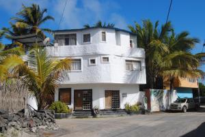 a white house with palm trees in front of it at Hostal Galapagos by Bar de Beto in Puerto Villamil