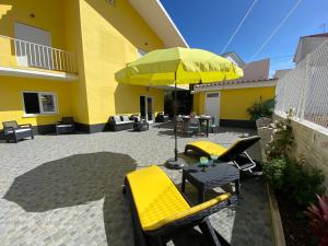 a patio with yellow chairs and an umbrella at cascaischillhouse in Cascais