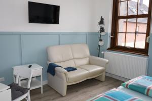 a living room with a white chair and a tv at CT-Apartments in Kerken