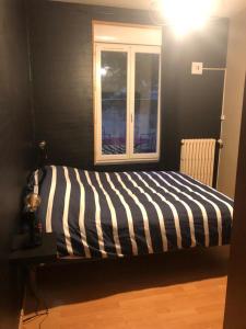 uma cama listrada num quarto com uma janela em Gîte St Thomas em Crépy-en-Valois