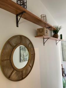 a wicker mirror on a wall with shelves at Villa des Chardons in Yport