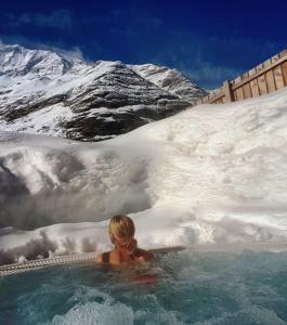 uma mulher numa banheira de hidromassagem com uma montanha coberta de neve em Hotel Restaurant Rosmarie em Pfelders