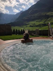 a woman in a jacuzzi tub with mountains in the background at Hotel Restaurant Rosmarie in Pfelders