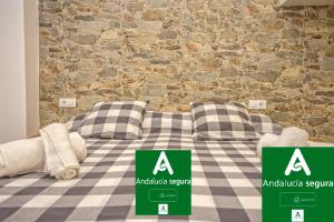 a bed with two pillows in front of a brick wall at Casa Jerez Alameda del Banco in Jerez de la Frontera