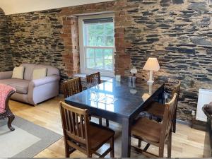 a dining room with a table and chairs and a stone wall at Period Coachhouse in Newbliss