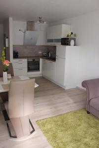 ein Wohnzimmer mit einer Küche mit weißen Schränken in der Unterkunft Ferienwohnung Miletta, Zentral Friedrichshafen Bodensee in Friedrichshafen