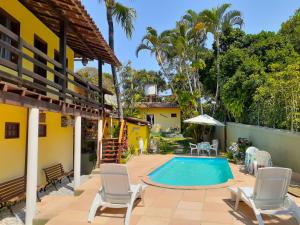 una casa y un patio con piscina y sillas en Pousada Arraial Lua Crescente, en Arraial d'Ajuda