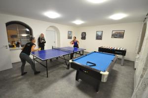 3 femmes jouant au ping-pong dans une salle avec des tables de ping-pong dans l'établissement Wellness Pension Fulda Černý Důl, à Černý Důl