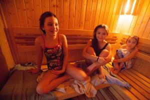 three young girls sitting in a sauna at Wellness Pension Fulda Černý Důl in Černý Dŭl