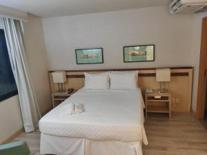 a bedroom with a large white bed and two lamps at Apart Hotel - Esplanada dos Ministérios - Centro de Brasília in Brasilia