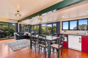 a kitchen and living room with a table and chairs at Pohutukawa Cottage - Matakana Holiday Home in Tawharanui