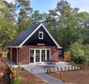 een rood bakstenen huis met een zwart dak en een patio bij 't Edelhert in Nunspeet