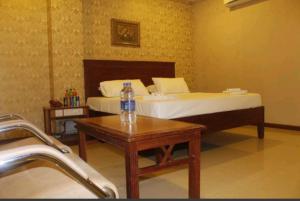 um quarto com uma cama e uma mesa com uma garrafa de água em Hotel Chitra Park em Tiruchendur