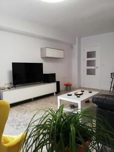 un soggiorno con una grande TV su una parete bianca di Casa Princesa Huelin a Málaga