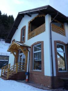 una casa con un portico nella neve di Pensiunea Popas Pop, Strambu-Baiut, Maramures a Băiuţ