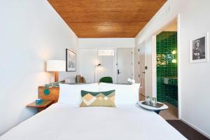 a bedroom with a white bed and a green wall at Hotel Magdalena in Austin
