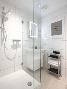 een glazen douche in een witte badkamer met een wastafel bij Charming WILHELM in Saarbrücken