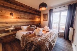 a bedroom with a bed with a wooden wall at Chalet La Perle de L'Oisans - Appartements d'Exception in Vaujany