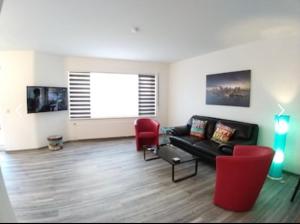 a living room with a black couch and red chairs at EXKLUSIVE Ferienwohnung mit Terasse und Garten in Einbeck, Zentrum! NEU!! in Einbeck +2 photos