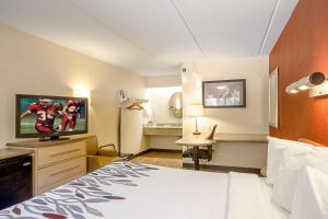 ein Hotelzimmer mit einem Bett und einem Flachbild-TV in der Unterkunft Red Roof Inn Canton in Canton