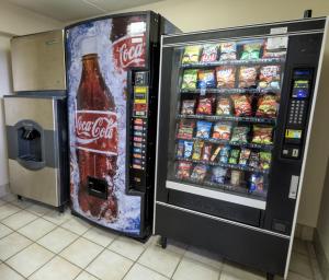 una máquina expendedora de refrescos de cocacola junto a un enfriador de bebidas en Red Roof Inn Lafayette, LA, en Lafayette