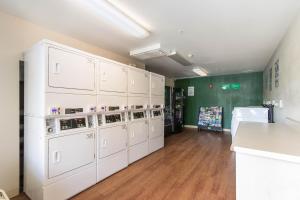 a laundry room with white cabinets and a green wall at HomeTowne Studios by Red Roof Fort Lauderdale in Fort Lauderdale