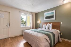 a bedroom with a large bed and a window at HomeTowne Studios by Red Roof Fort Lauderdale in Fort Lauderdale