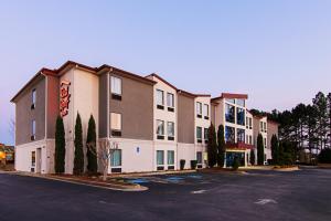 a large apartment building in a parking lot at Red Roof Inn Locust Grove in Locust Grove