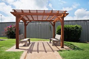 a wooden pergola with two benches in a yard at Red Roof Inn PLUS+ Nashville Fairgrounds in Nashville