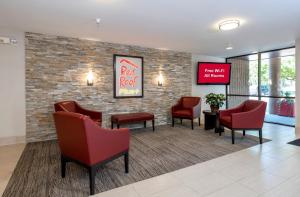 una sala de espera con sillas rojas y una pared de roca roja en Red Roof Inn PLUS Boston - Mansfield - Foxboro, en Mansfield