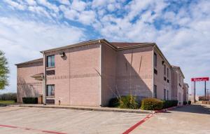 een lege parkeerplaats voor een bakstenen gebouw bij Red Roof Inn Fort Worth - Saginaw in Fort Worth