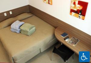 Cama pequeña en habitación con mesa en Total Hotel, en São Paulo