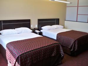 a hotel room with two beds with red sheets at Red Roof Inn & Suites Beaumont in Beaumont