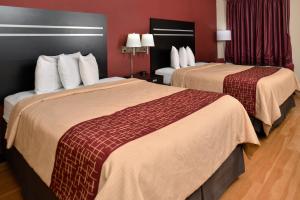 two beds in a hotel room with red walls at Red Roof Inn Cartersville-Emerson-LakePoint North in Cartersville
