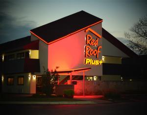 a building with a red roof and a neon sign at Red Roof Inn PLUS+ University at Buffalo - Amherst in Amherst