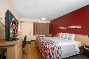 a hotel room with a bed and a flat screen tv at Red Roof Inn Mystic - New London in New London