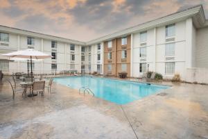 a pool with chairs and an umbrella in front of a building at Red Roof Inn Knoxville Central – Papermill Road in Knoxville