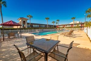 a patio with a table and chairs next to a swimming pool at Red Roof Inn PLUS+ St. Augustine in Saint Augustine