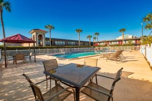 a patio with a table and chairs next to a swimming pool at Red Roof Inn PLUS+ St. Augustine in St. Augustine