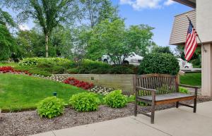 un banco de madera en un jardín con bandera en Red Roof Inn Cleveland - Mentor/ Willoughby, en Willoughby