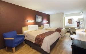 a hotel room with two beds and a blue chair at Red Roof Inn Cincinnati - Sharonville in Sharonville