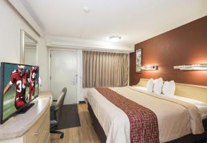 a hotel room with a bed and a flat screen tv at Red Roof Inn Cincinnati - Sharonville in Sharonville