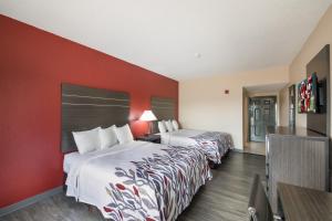 two beds in a hotel room with red walls at Red Roof Inn & Suites Austin East - Manor in Manor