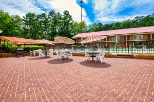 un patio con mesas, sillas y sombrillas en Red Roof Inn Hot Springs, en Hot Springs