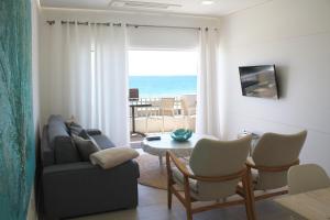 ein Wohnzimmer mit einem Sofa und einem Tisch in der Unterkunft Front Sea Apartment in Quarteira