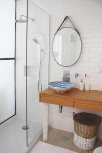 een badkamer met een wastafel en een douche met een spiegel bij Front Sea Apartment in Quarteira