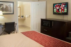 a hotel room with a bed and a flat screen tv at Red Roof Inn Ardmore in Ardmore