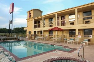 a hotel with a swimming pool in front of a building at Red Roof Inn Ardmore in Ardmore